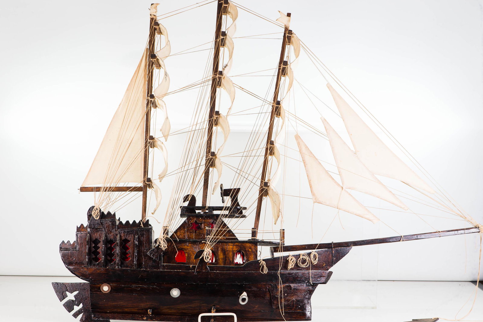 Folk Art Wooden Ship's Model: Approximately 33"H x 40"L. Handmade wooden model with canvas masts, and skull and crossbones stencils. Missing base stand.