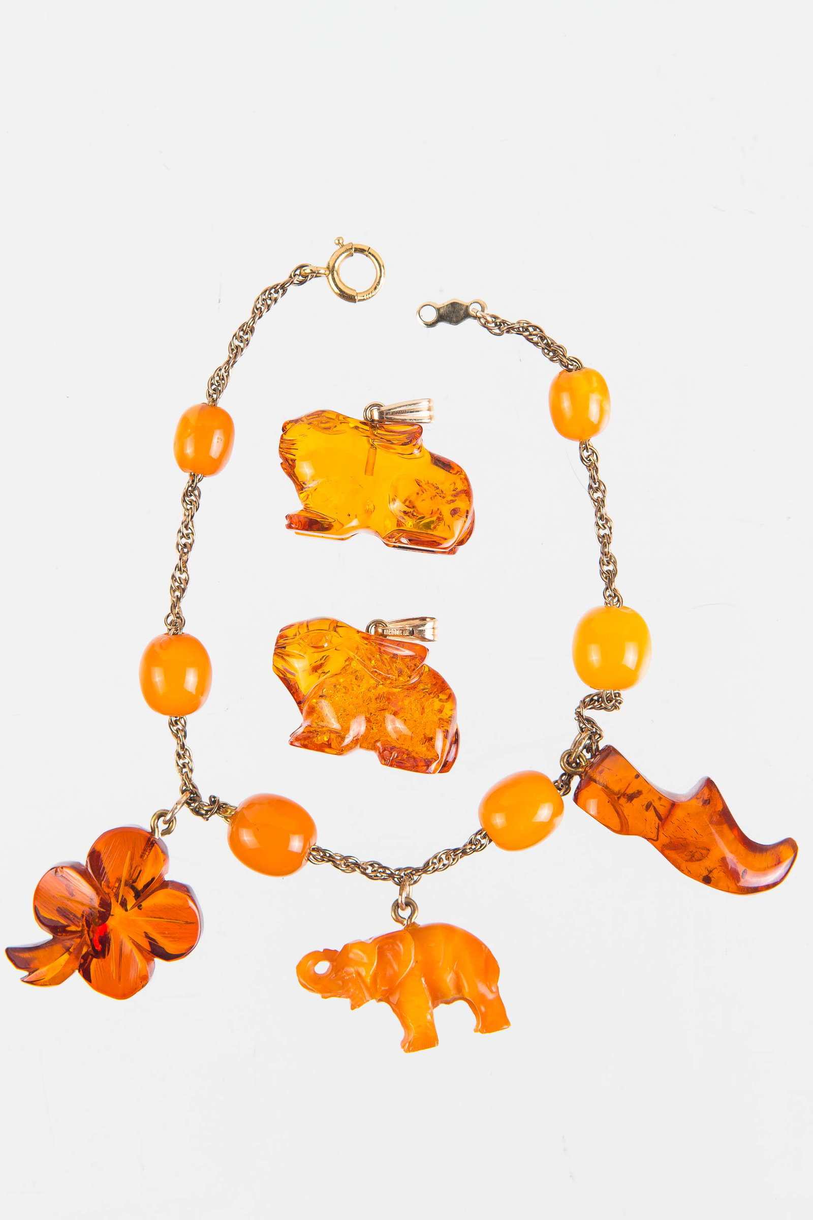Vintage Estate Amber Jewelry: Charm bracelet with butterscotch and Baltic amber charms, including carved elephant, four leaf clover, Dutch shoe, and cabochon butterscotch beads on gold filled bracelet. Lot also includes carved amb