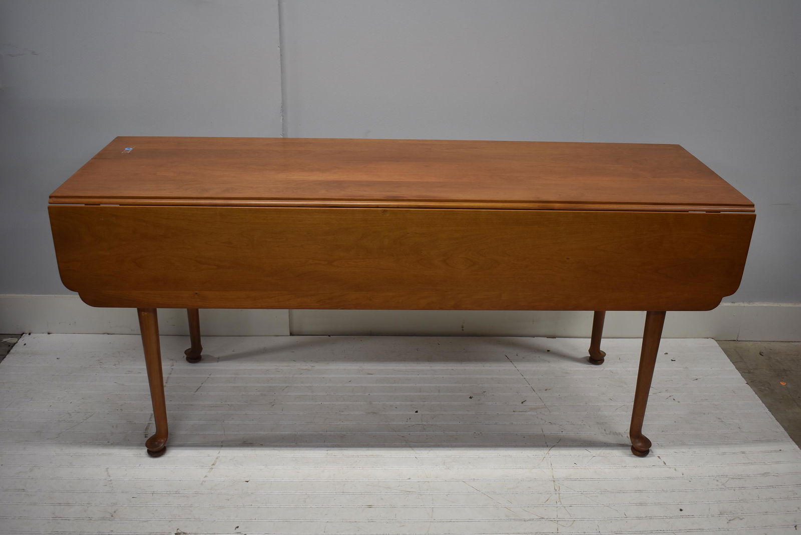 Drop Leaf Harvest Table: Item measures approximately 30"H x 66"L x 22"W (close) and 43"W (open). Cherry construction, it stands on a Queen Anne paw foot.