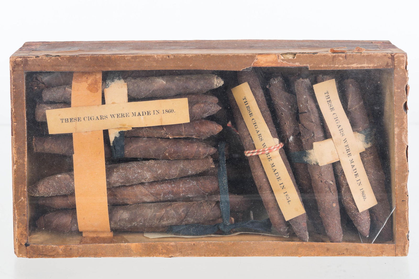 1860s Cigars in Glass Top Case: Lot includes 3 bundles of cigars, tagged "These were made in 1854. 1860, and 1861". Cigars appear to be complete and are in a glass top cigar box.