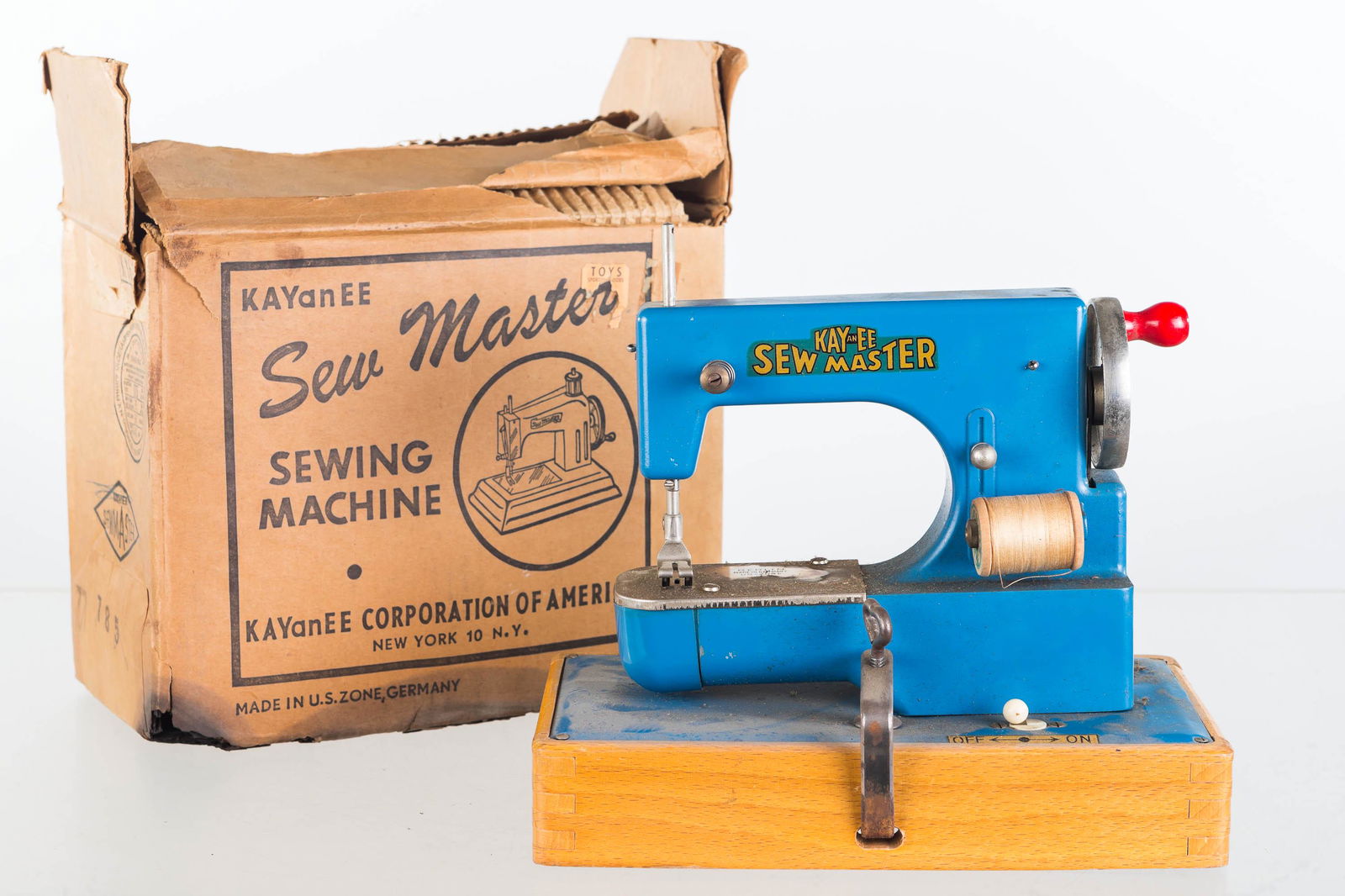 KayanEE Sew Master Sewing Machine in OB: Item measures approximately 7"H x 8.5"L. Clean original surface with decals. Arm works when turned by handle. Oxidation to contacts at battery terminals. Item has original box. Sewing machine marked "