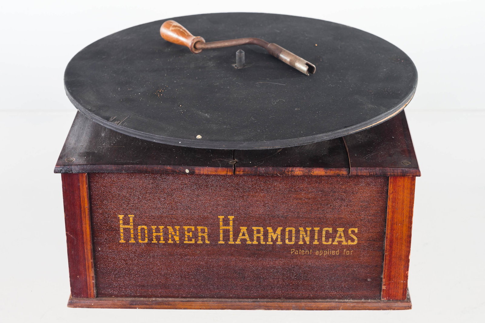 Hohner Harmonica Turn Table Display: Item measures approximately 6"H including turn table x 11"W x 11"D. Wind up display with Hohner advertising on three sides. Item retains crank that turns slowly when wound. Wooden top has crack under