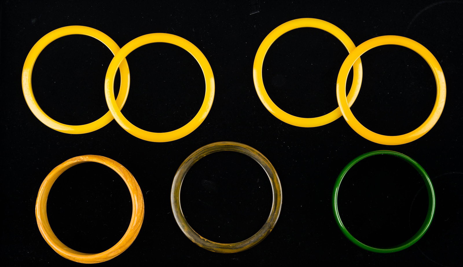 Vintage Bakelite and Plastic Bangles: Yellow heavily carved wide bakelite bangle (tested), wide green bakelite bangle (tested), and five thin bakelite-like bangles.