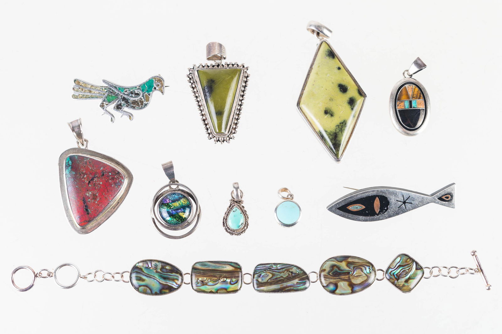 Sterling Pendants and a Bracelet: Lot includes 6 sterling pendants with turquoise, green, and multicolor polished stones, sterling bracelet with abalone, sterling inlaid bird, and a sterling inlaid fish.