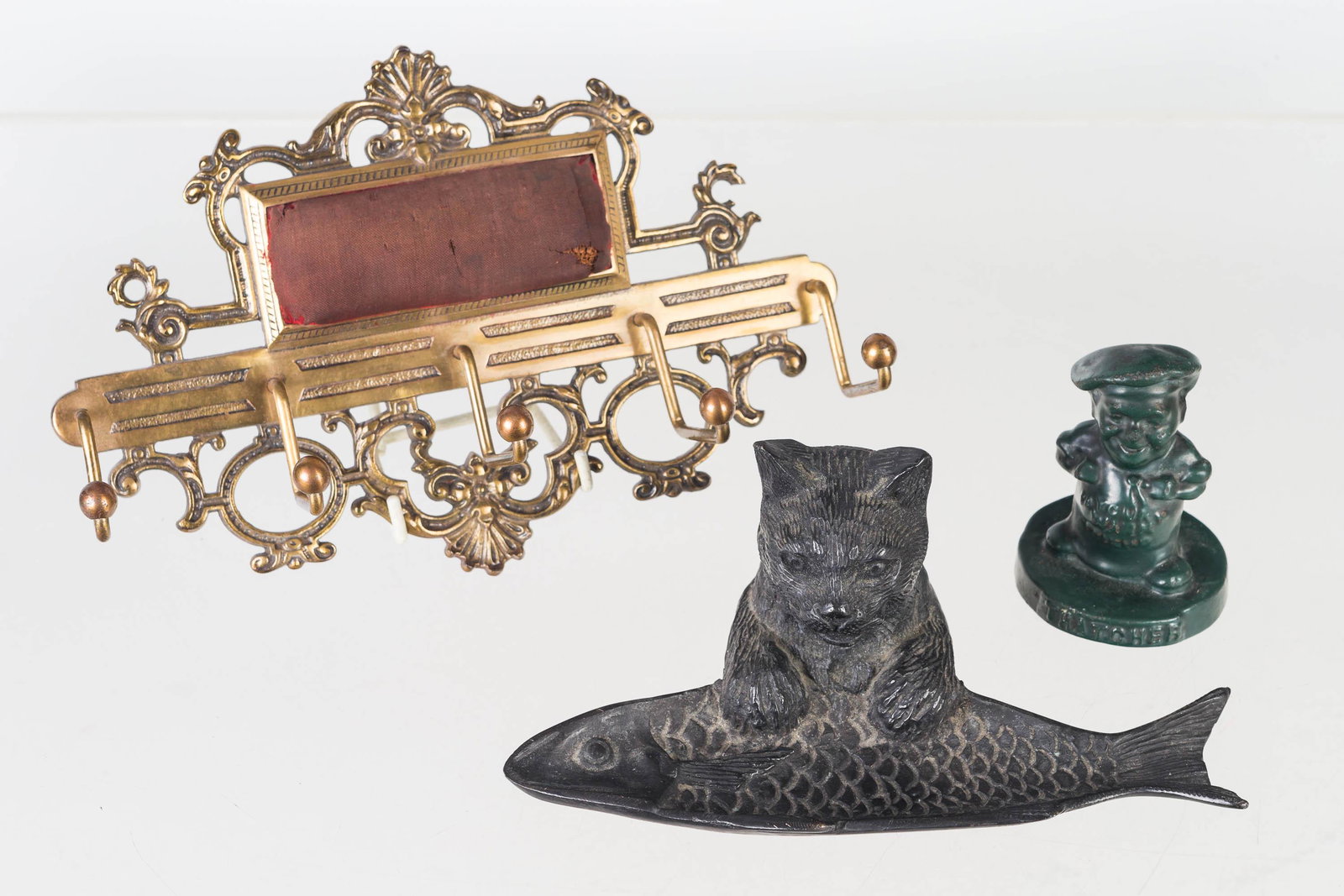 Cast Iron and Brass Figural Grouping: Lot includes a cast iron advertising figure (3.5"H), cast iron cat and fish pen holder, and a late Victorian era brass tie rack with pin cushion.