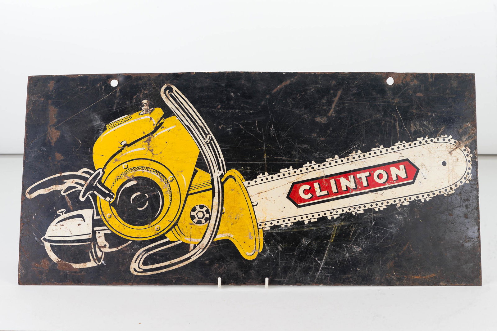 Clinton Metal Chainsaw Display Sign: Item measures approximately 11"H x 23"W. Clinton chainsaw on each side. Heavy gauge metal sign, shows common wear.