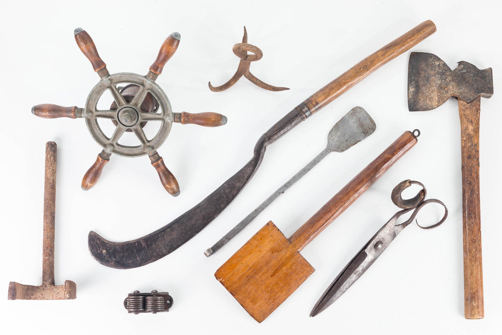 Tool Grouping, 19th / 20th C: Lot includes a ship's wheel yarn winder, large vintage shears with loss to leather handles, a hatchet, a triple hook, wood and metal spatulas, a wagon wheel hub puller, a knife sharpener, and a hand w