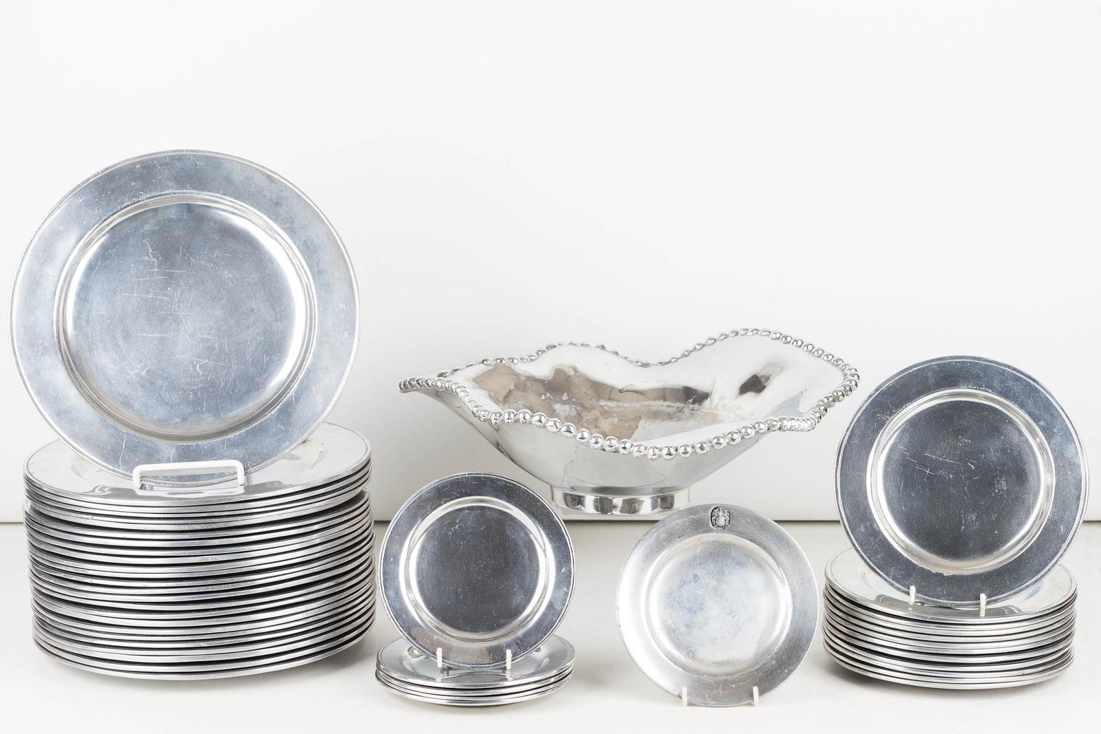 Collection of Wilton Pewter Dinnerware: Lot includes 25 10.5" dinner plates, a Mariposa abstract fruit bowl with beaded edge, 12 dessert plates, and 6 bread and butter plates. Plates marked Wilton - Columbia, PA (Pennsylvania company/Wilton
