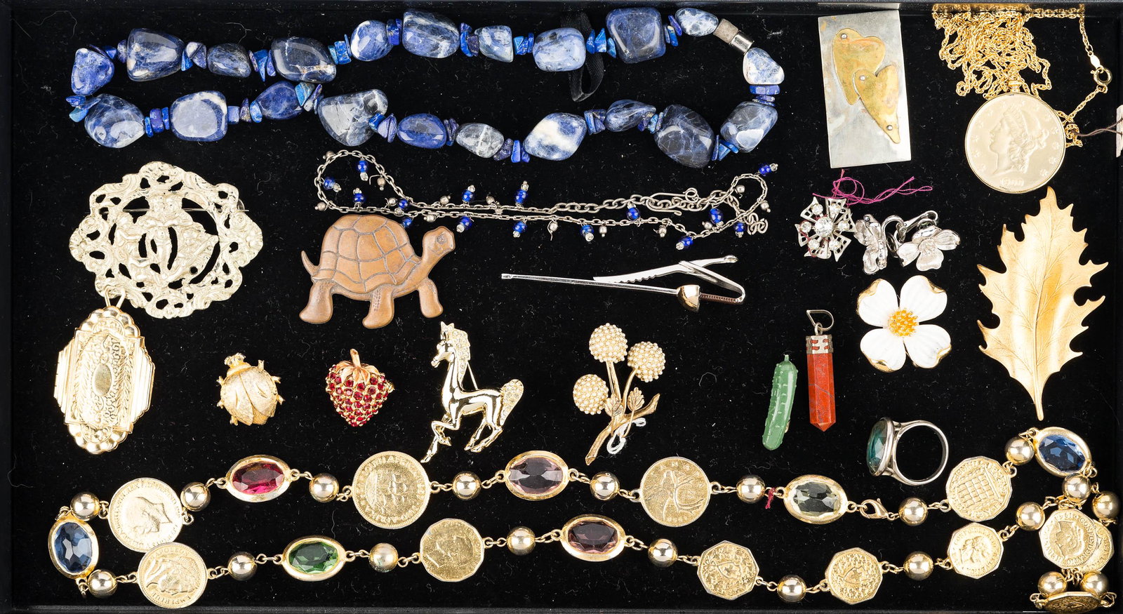 Coin and Figural Costume Jewelry: a large coin necklace with faceted stones, necklace with faux $20 gold piece, figural horse, beetle, and strawberry pins, a large lapis type necklace, Art Deco locket, ad related costume jewelry.