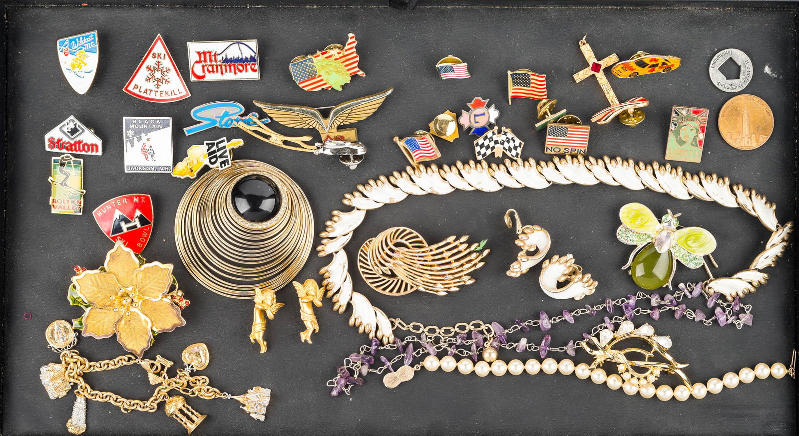 Costume Jewelry and Lapel Pins: a wide selection of enameled lapel pins, a Trifari gold tone comet brooch, Trifari white enameled necklace and earring set, enameled bumble bee pin, charm bracelet, and other costume jewelry.