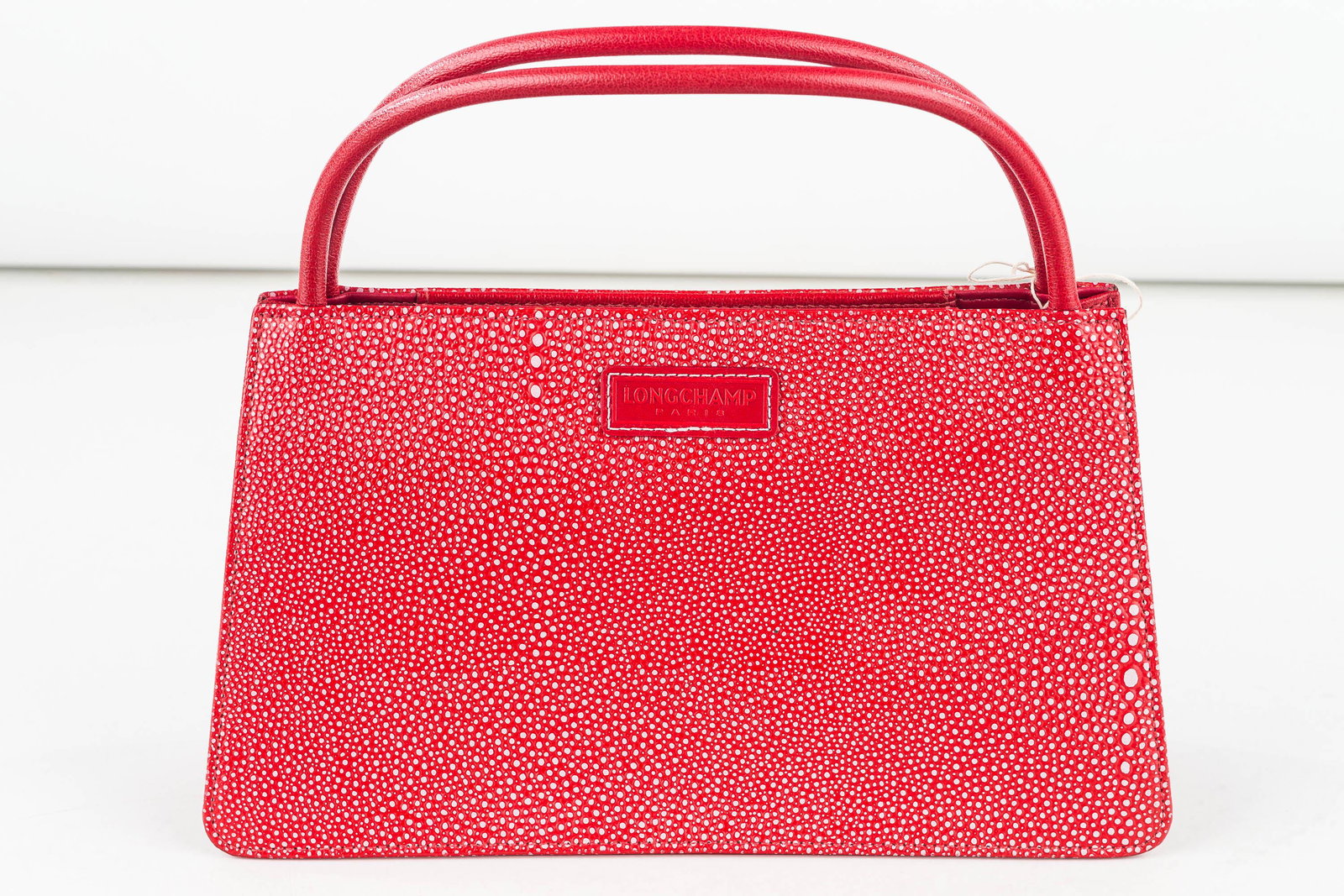 Red Longchamp Pebbled Leather Purse: Small red leather purse approx 11" x 6 1/2" with magnetic inside closure, also inside, one open and one zippered pocket with Longchamp and logo on the pull. It is stamped 92251 EKP on the back of the 