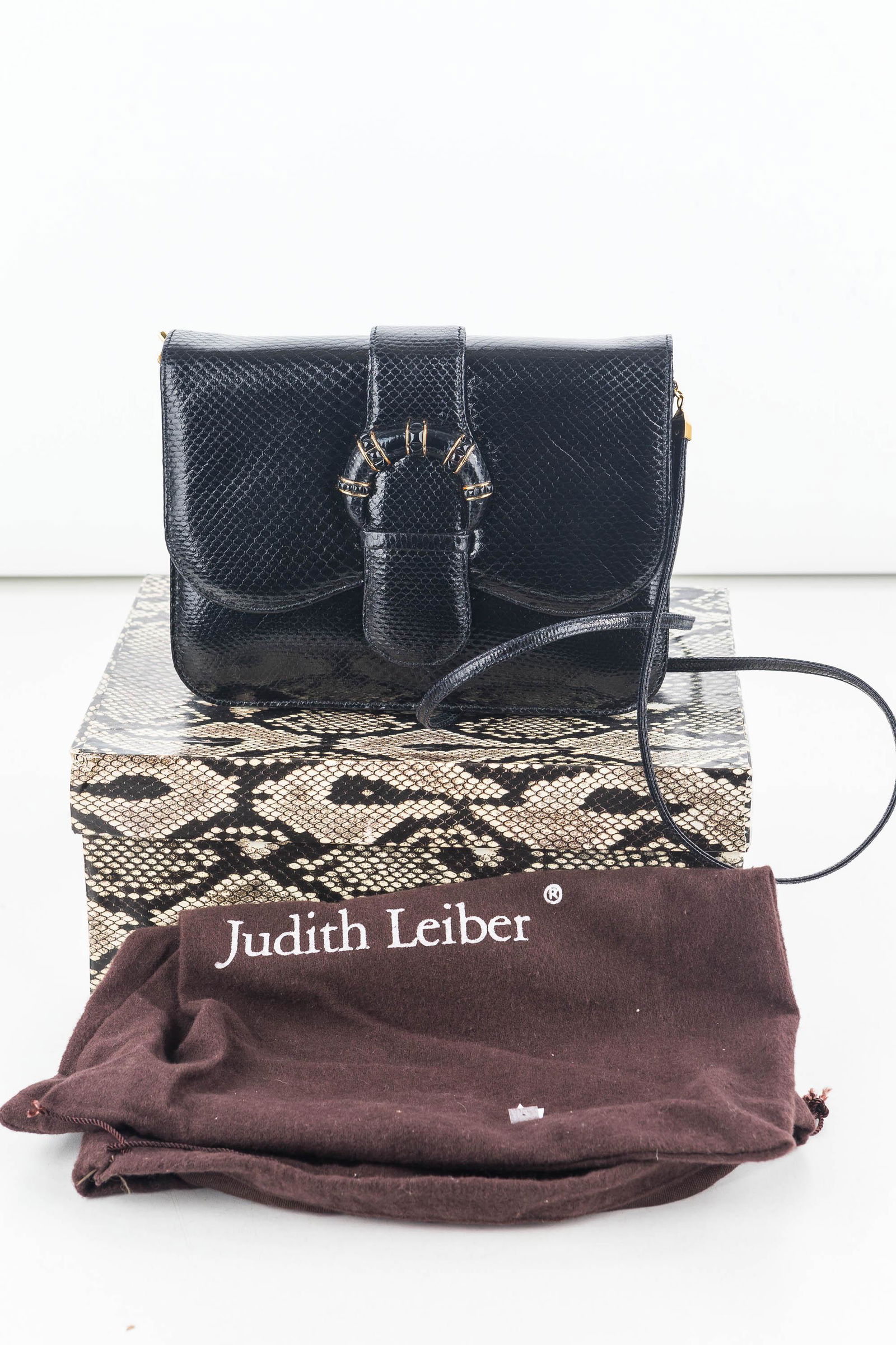 Judith Leiber Black Reptile Purse with Long Strap: It is a structured rectangle shape approx 7 1/2" x 6" x 2 1/2", flap front magnetic closure with faux buckle, gold tone and black glass accent, strap accent. It has a 1/4" wide 42" detachable strap wi