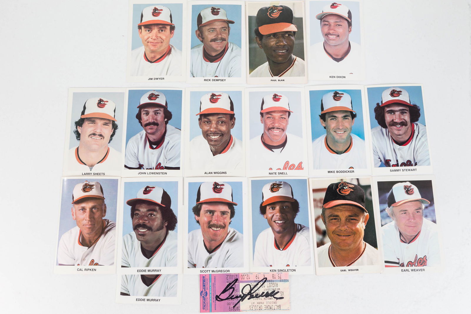 Vintage Orioles Photos, and Boog Powell Autograph: Lot includes 17 Orioles 3x5 photos, including Cal Ripken, Eddie Murray, Ken Singleton and others (16 are clean with good corners, Paul Blair shows wear) and an autographed Boog Powell ticket from Camd
