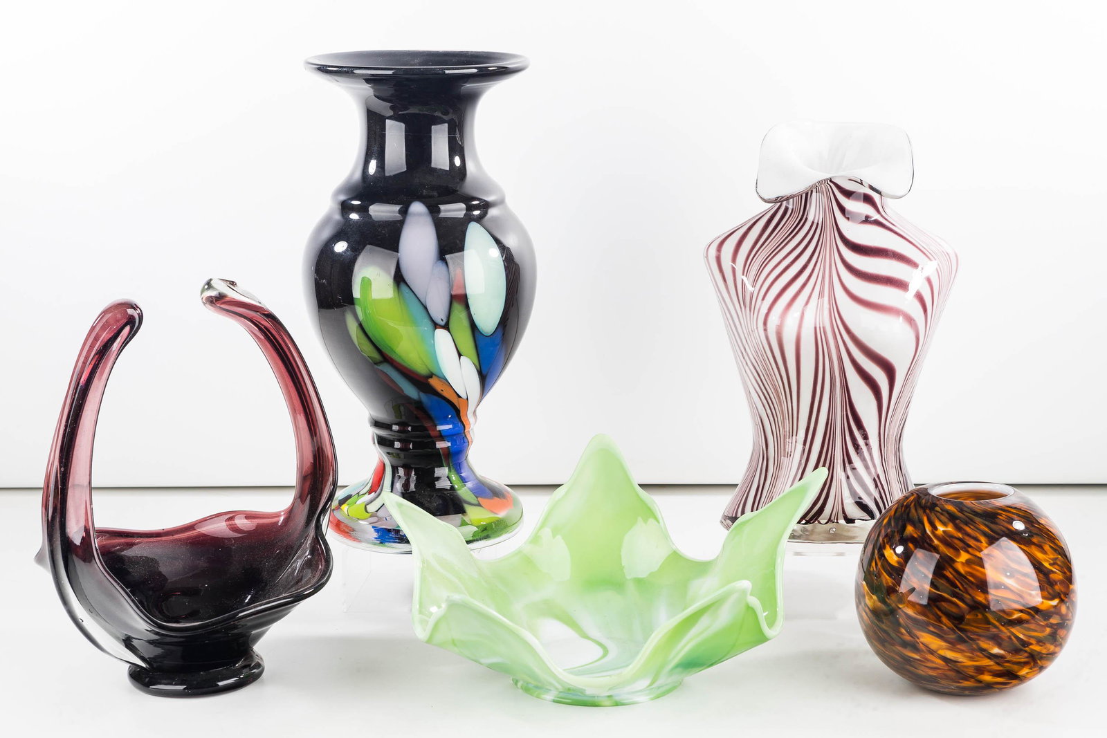 Large Czech Art Glass Vase and Others: Lot includes a Czech Republic art glass vase (14"H), a striated art glass vase in the form of a woman's body (9"H), a mottled brown rose bowl, a green agate style 1970s bowl, and a purple handled art 