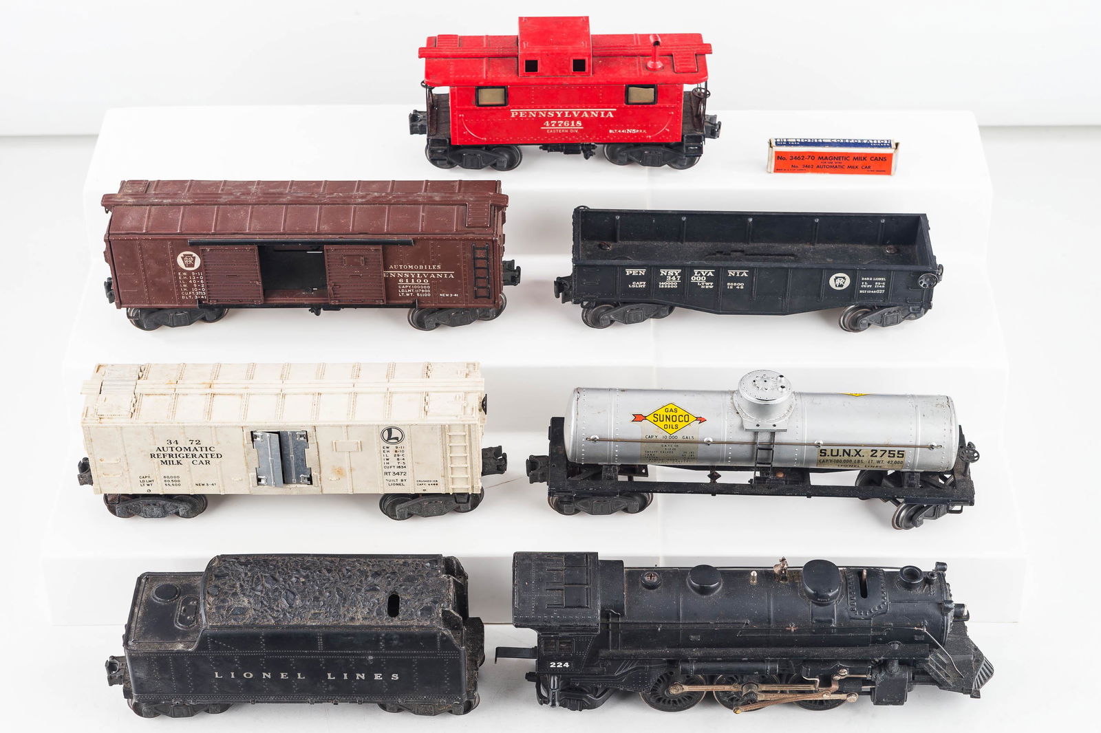 Vintage O Gauge Lionel Train: Lot includes a 224 engine, a 2446W tender, an active automatic refrigerated milk car (has a set of magnetic milk cans in original box), a 477618 caboose, and various other cars. Tender is missing a co