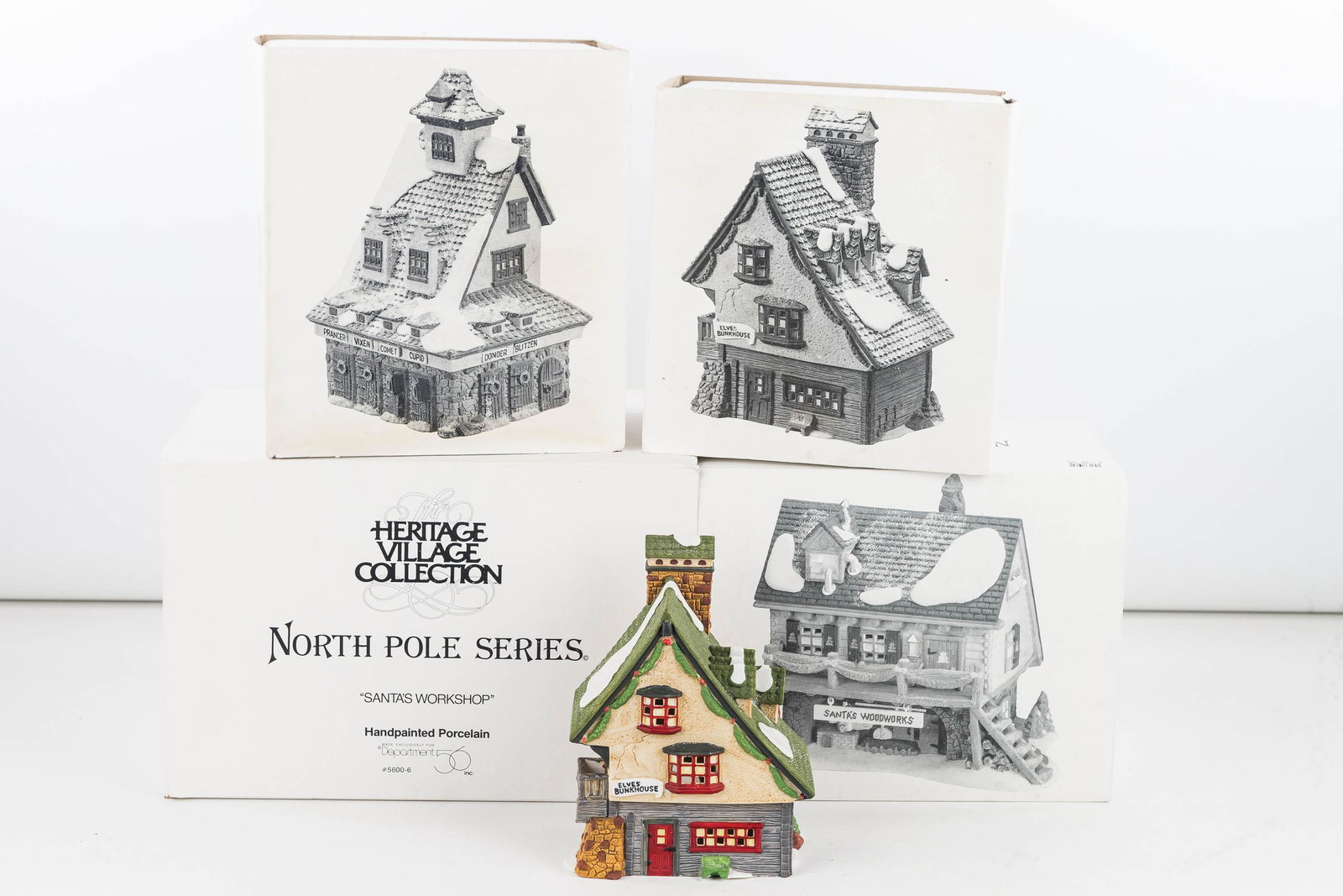 Department 56 Collection/North Pole Series: Four pieces including Santa's Workshop, Santa's Woodworks, Elf Bunkhouse and Reindeer barn. In original boxes