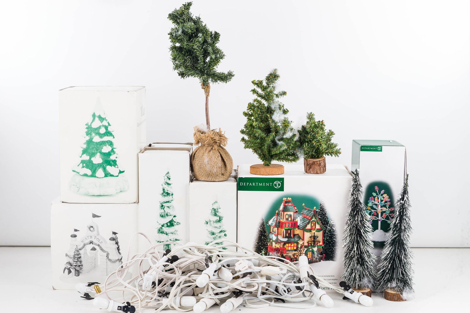 Department 56 Collection/North Pole Series: Including North Pole gate, ornament Works Revolving Snow cap tree and others. Eight total pieces. Lot also includes a string of Christmas lights and small various sized faux trees. One tree has Depart