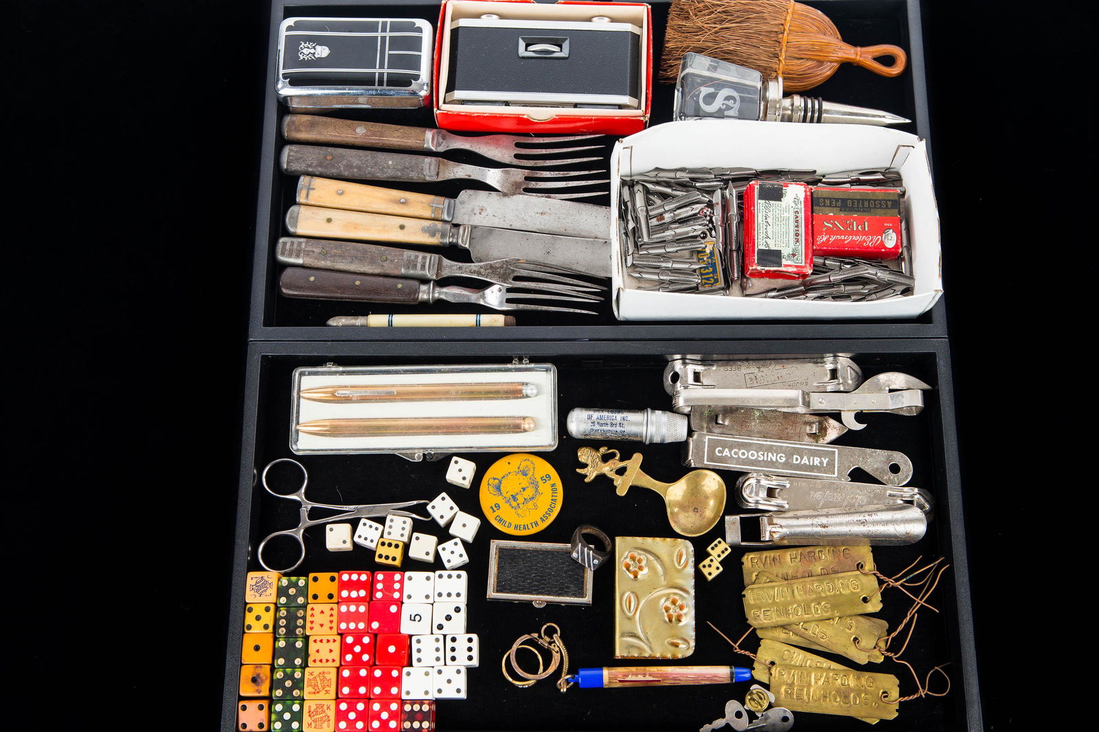 Two Trays of Eclectic Mixed Groupings: Including wooden handled knives and forks, a tilt-o-matic pen and pencil set, collection of dice, advertising bottle openers, and other items