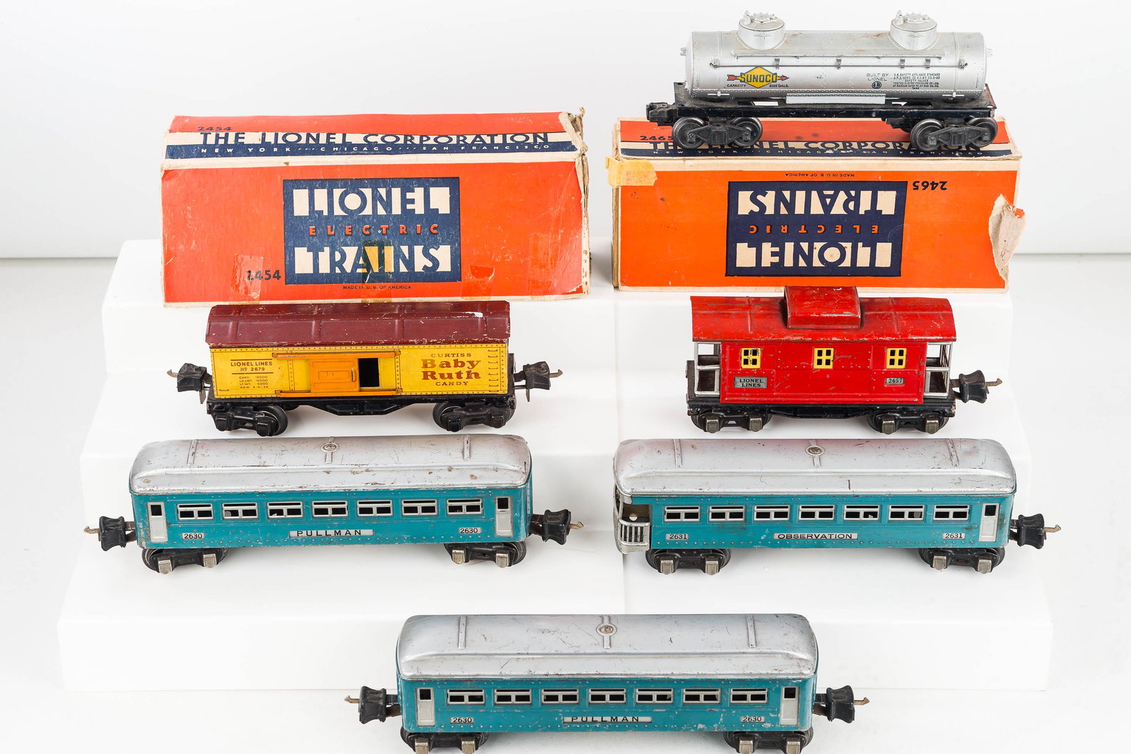 Vintage Tin Lionel Train Cars: Including three Pullman passenger cars, Caboose #2657 , a tanker car with metal base and plastic body and tin litho "Baby Ruth" car. Toys show common wear.