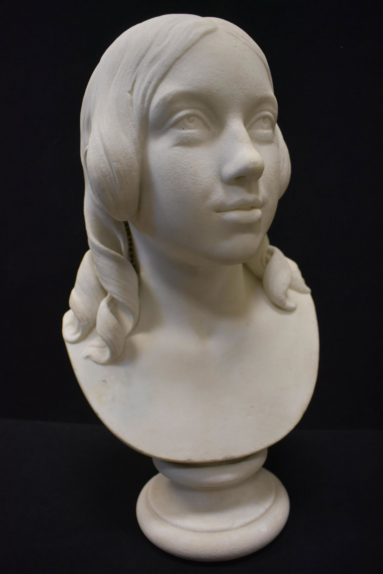 Female Bust Hiram Powers Style: Bust measures approx. 18" high depicts a young woman with flowing hair and is the style of Hiram Powers. She is marble or a similar material and weighs over 30 lbs, special shipping consideration requ