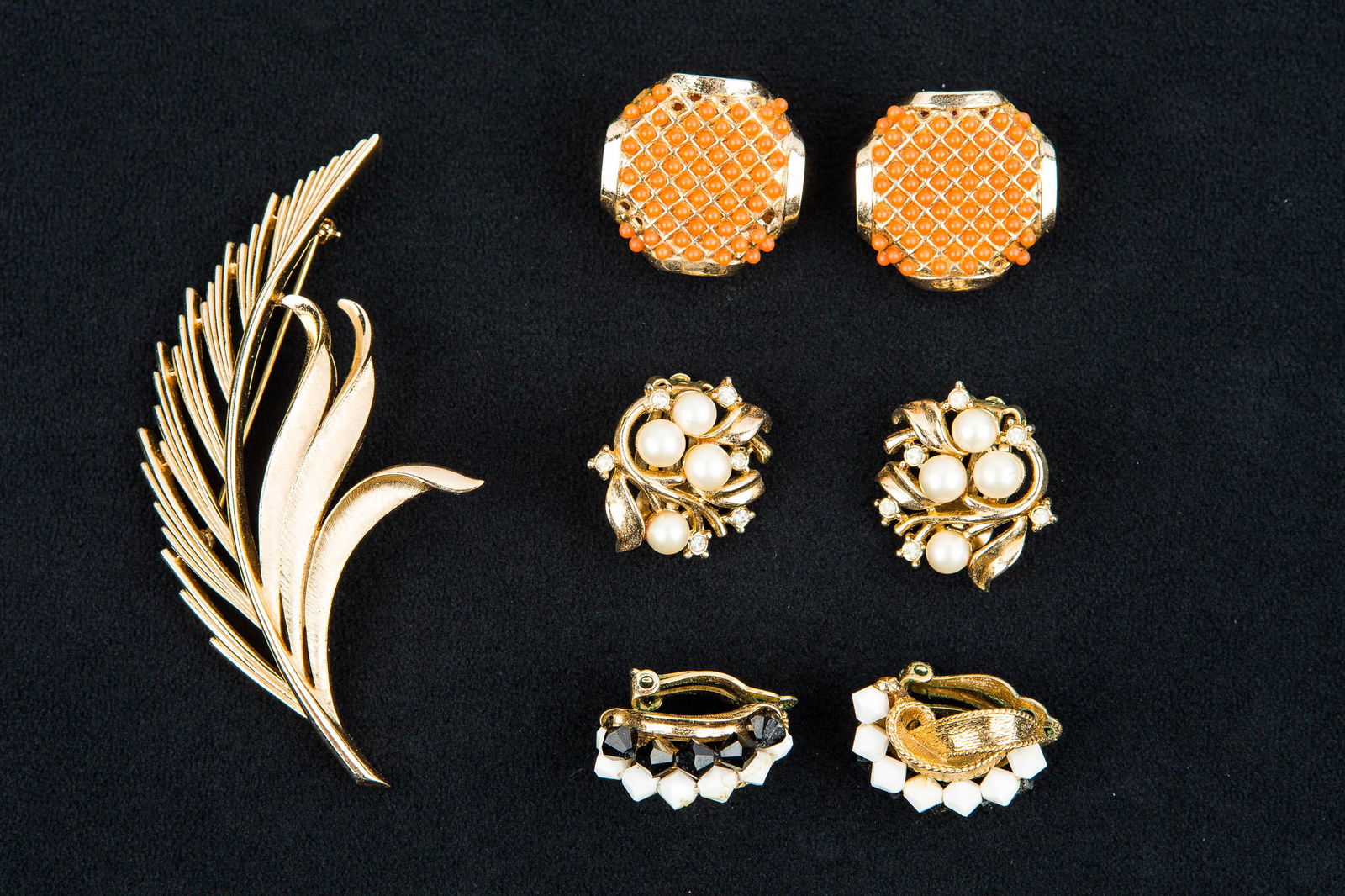 Vintage Trifari Jewelry: Vintage signed Trifari feather style brooch, Trifari pearl clip earrings and signed caner black and white clip earrings.