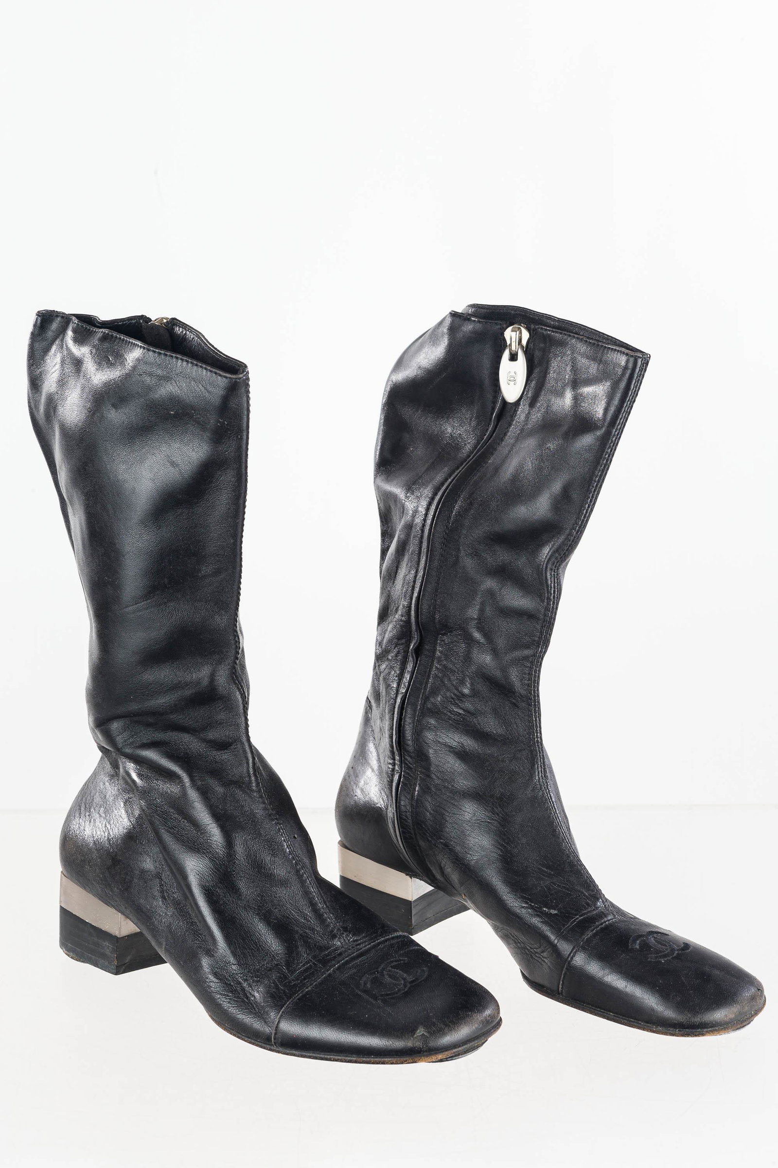 Designer Chanel Boots: These original signed Chanel kidskin black leather vintage boots feature the iconic interlocking C's logo on the toe, and "Chanel" in block letters on the brushed silver heel. Light wear. Sz 5.5B, Ita