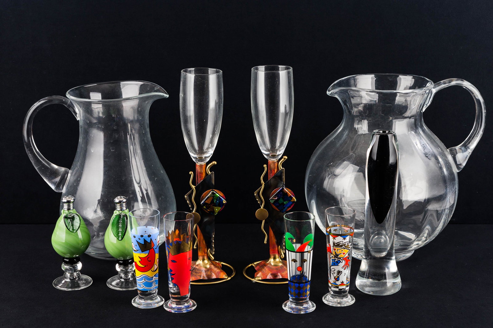 Art Glass and Related: Lot includes a pair of art glass salt and peppers with etched signatures; an art glass bud vase; two water pitchers (one is hand blown); a pair of decorative champagne flutes, and double shot glasses.