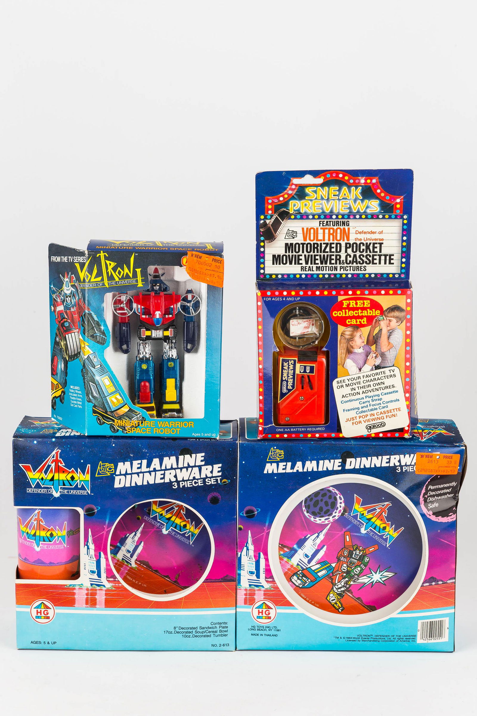 Volton Mixed Toy Grouping 1984: Including (2) dinnerware sets, a Voltron motorized movie viewer and cassette, and a Voltron Miniature Warrior Space Robot. All items are new in box and dated 1984.