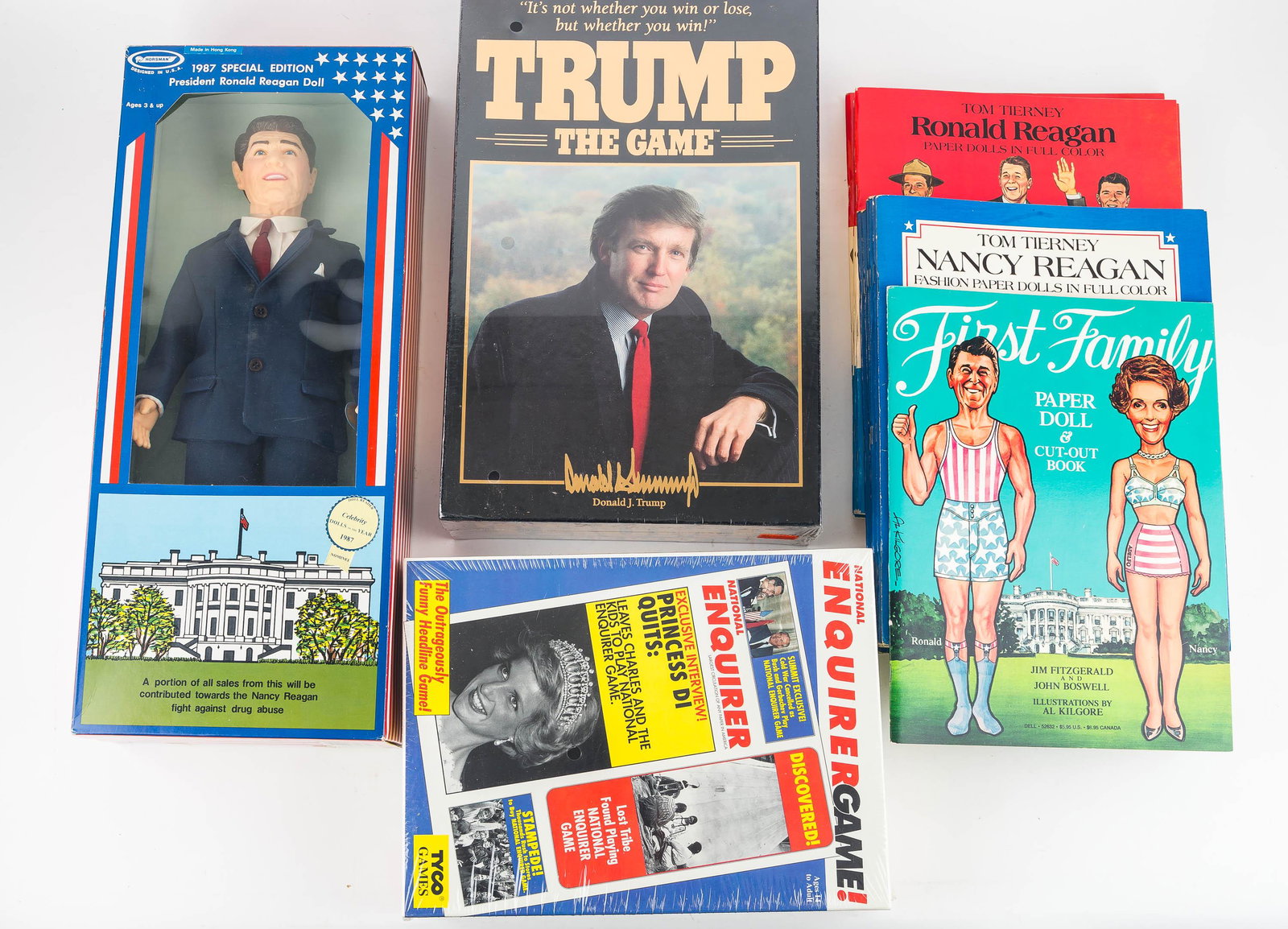 Political Games and Paper Dolls: Including The Enquirer Game (1990), Trump the Game 1989, 1987 Ronald Regan doll, and (11) Ronald Regan related paper doll cutout books, unused, produced by Dover Catalog and dated 1984.
