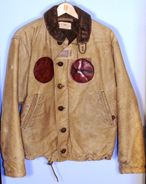 WWII interesting cloth coat: WWII Navy Lt Foul weather Flight Jacket w/two leather patches on front, one w/ a bomb or torpedo with the #84. This is an interesting cloth coat w/ brass anchor buttons. Theater made capt. bars on col