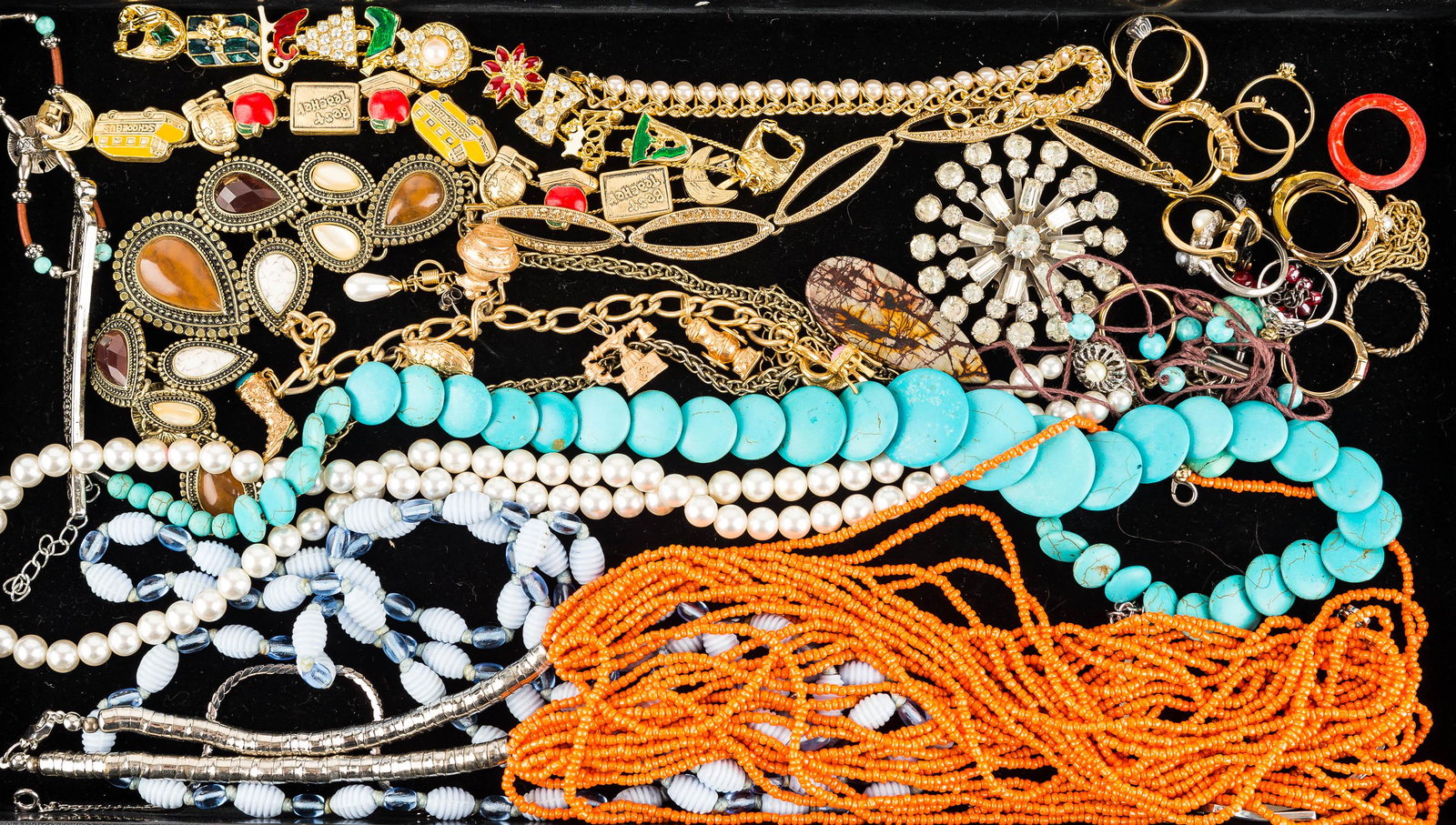 Necklaces, Bracelets, Rings, & Brooch: an orange multistrand beaded necklace, a teardrop style necklace marked "C", a turquoise style disc necklace, approx. (15) decorative rings, a charm bracelet, a holiday bracelet, and related costume j