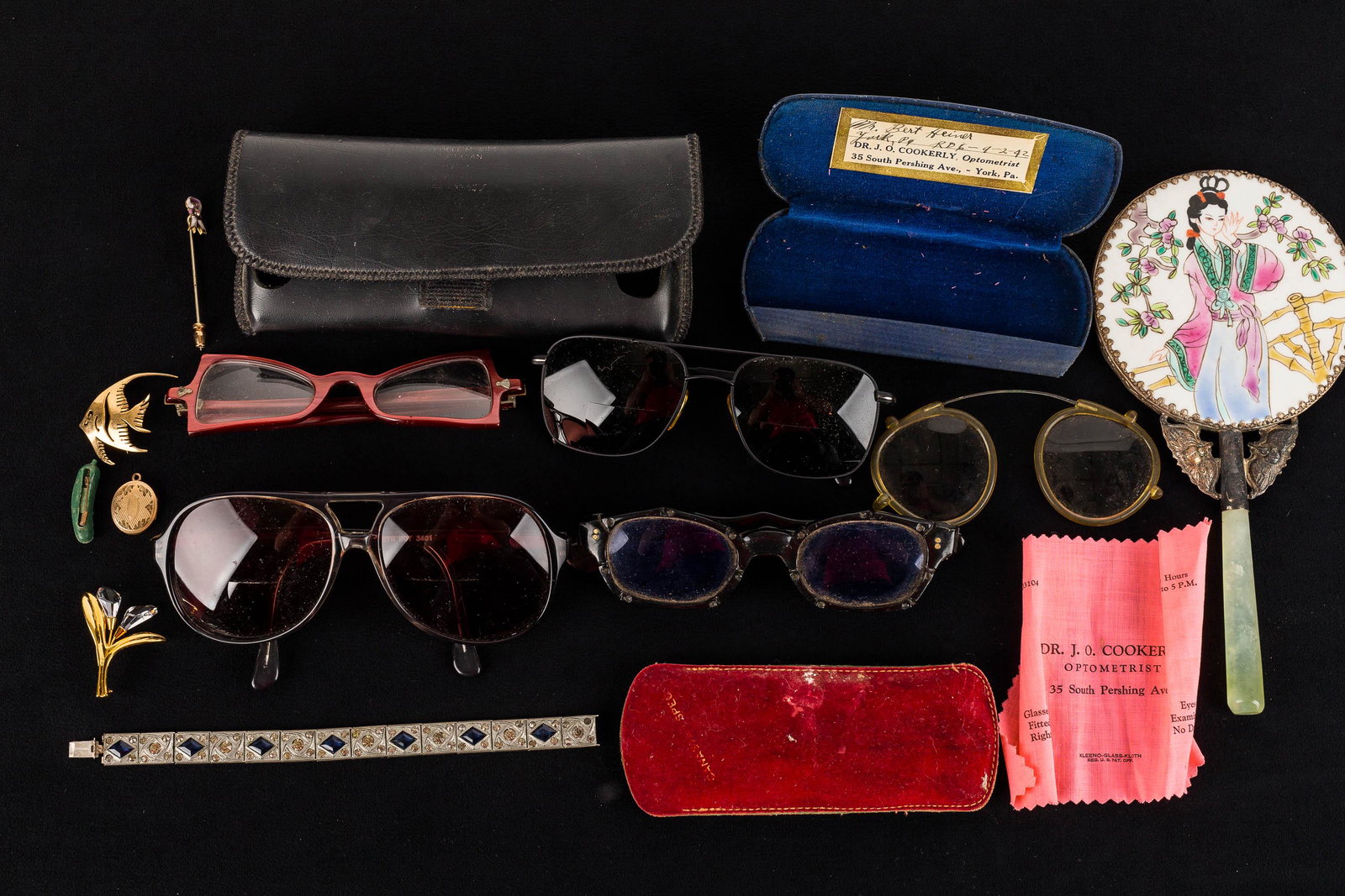 Vintage Sunglasses & Costume Jewelry: This eclectic grouping includes a pair of clip-on sunglasses, a pair of pink ladies' geometric glasses, a pair of S.M. Big Boys, a pair of black frame sunglasses in case, a vintage hand mirror with ge