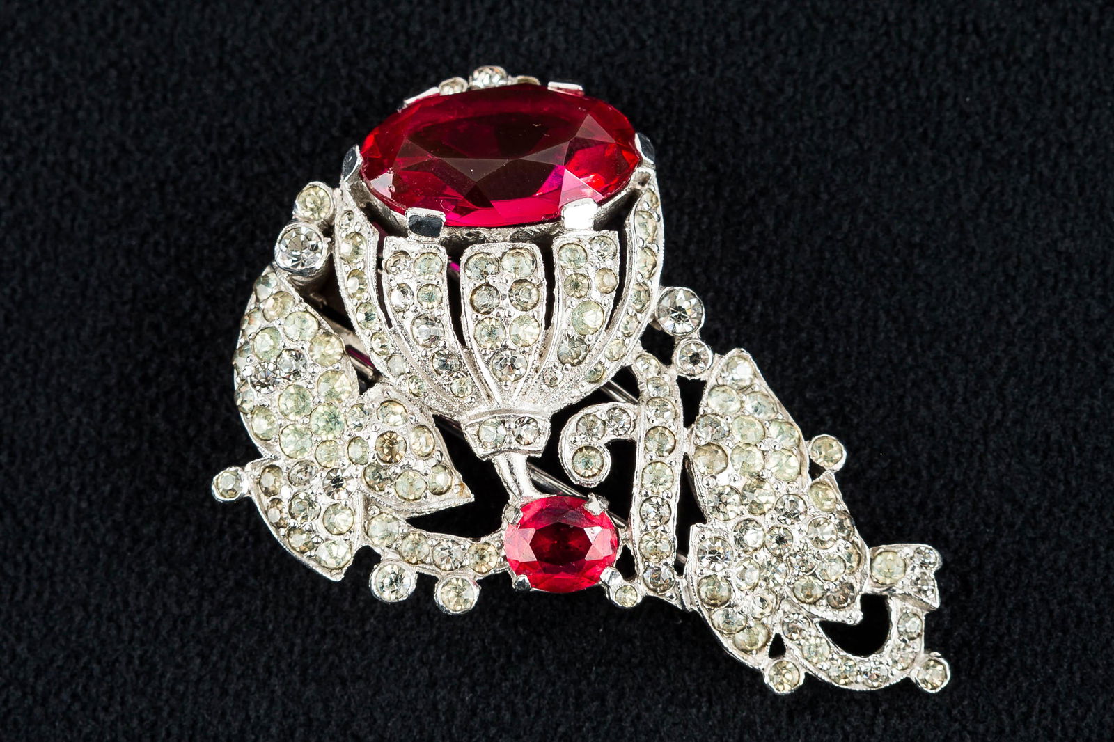 Trifari Vintage Fur Clip: This fur clip is signed "Trifari" with crown c. 1940s. It is white chrome with red and clear stones in the shape of a flower. It is in excellent condition and measures approx. 2" L.