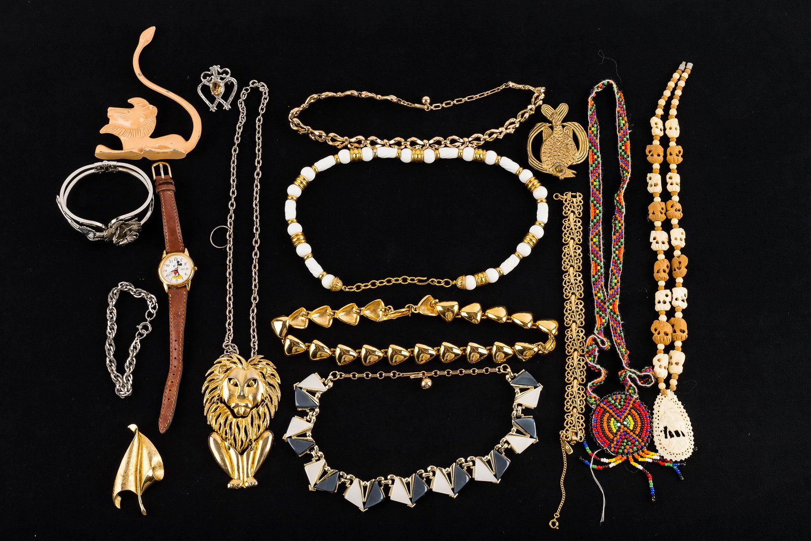 Eclectic Jewelry Collection: a large hinged lion pendant on chain, various gold tone necklaces, a hinged silver tone floral cuff, Calva Studios brass fish brooch, a metal lion ring holder, a gold tone Monet reticulated bracelet m