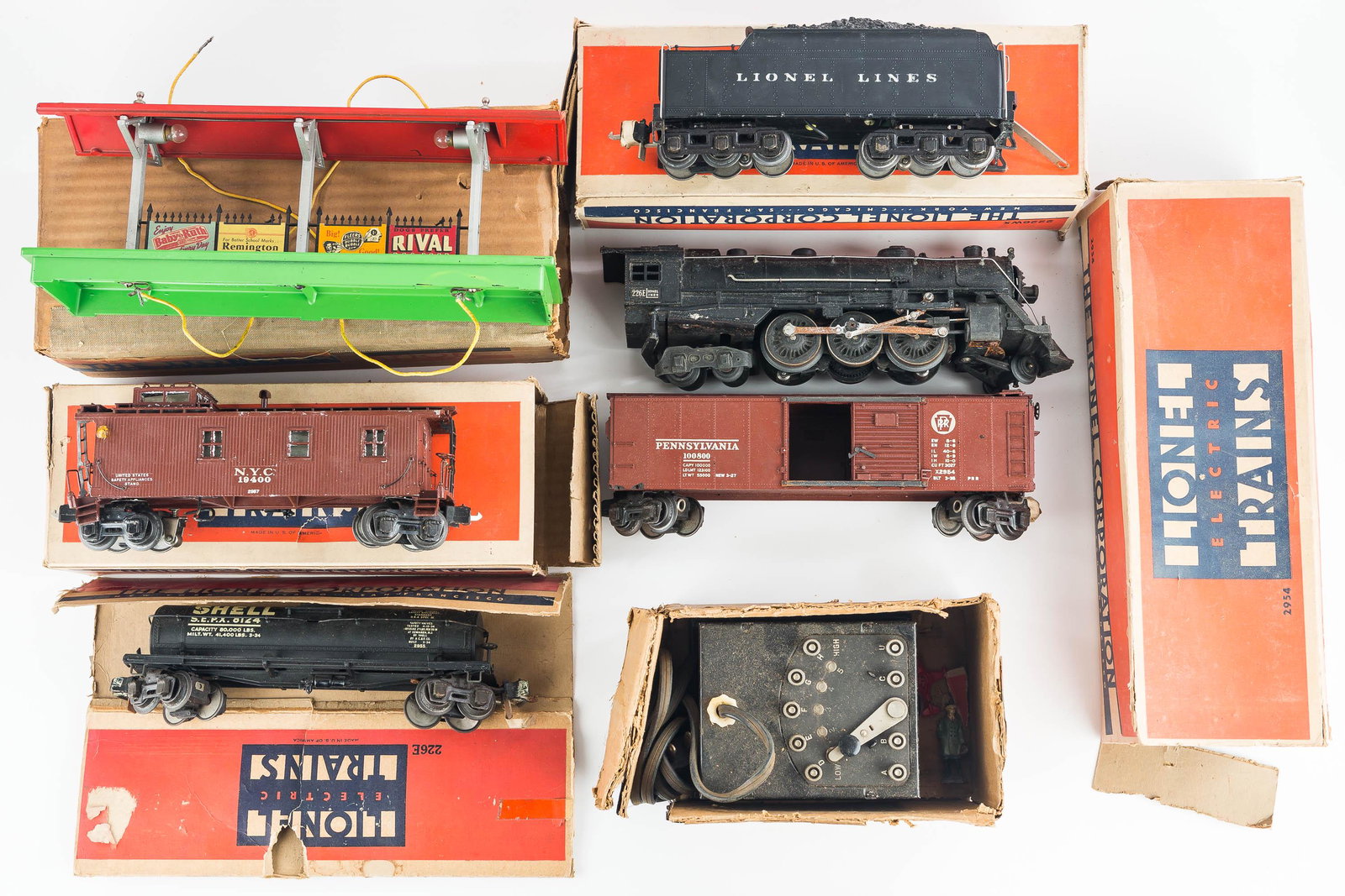 Vintage Lionel "O" Gauge Train: This group of trains and related pieces includes a 266E Engine, 226WX Tender, 2954 Boxcar, a Shell Oil car, a 2957 Caboose, a Type T Multivolt Transformer, and a train station pavilion with glue on ba