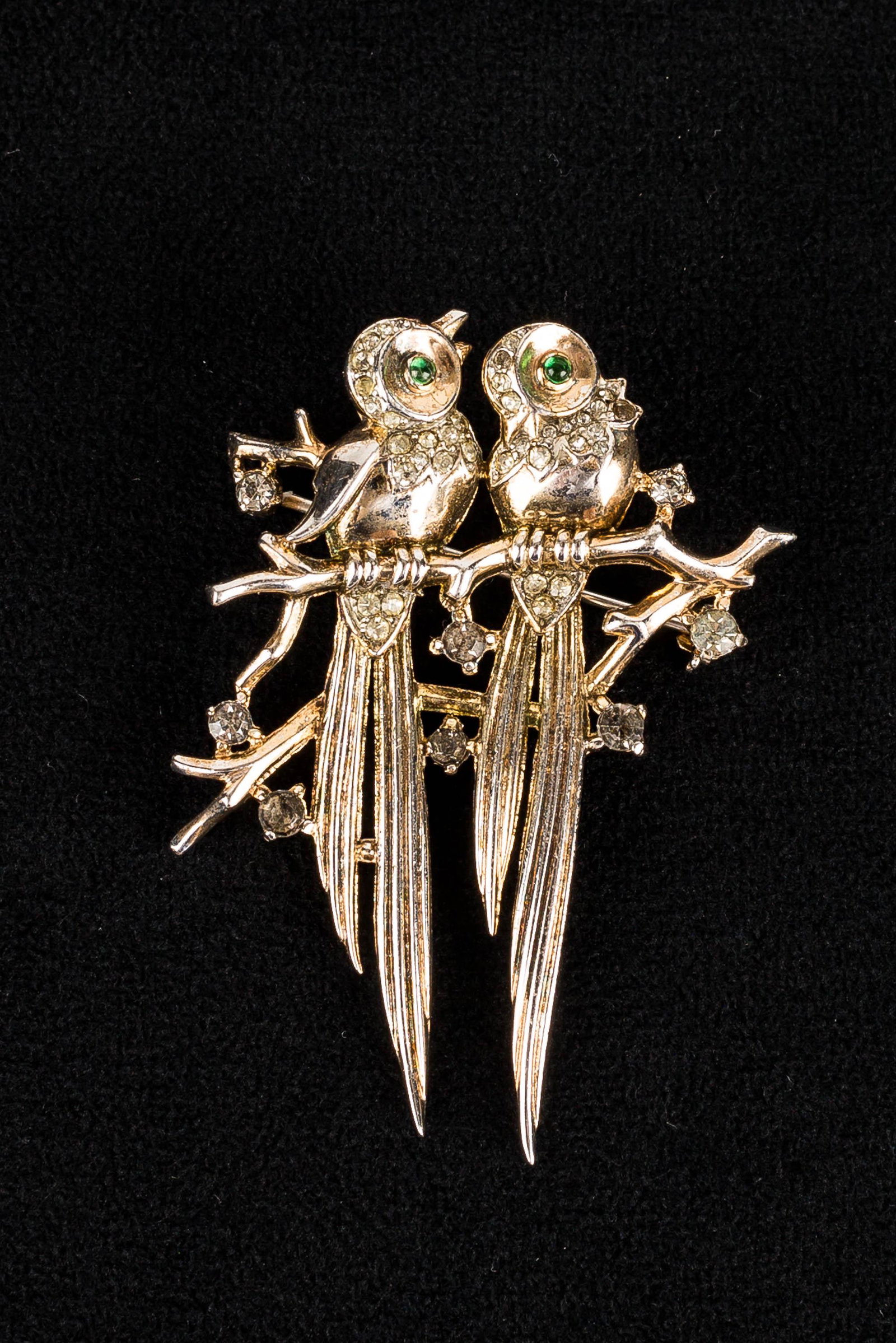 Sterling Trifari Double Bird Brooch: This Trifari sterling silver brooch depicts two birds sitting on a branch; the birds have green rhinestone eyes and clear rhinestone highlights. The brooch is marked "Trifari sterling", and measures a