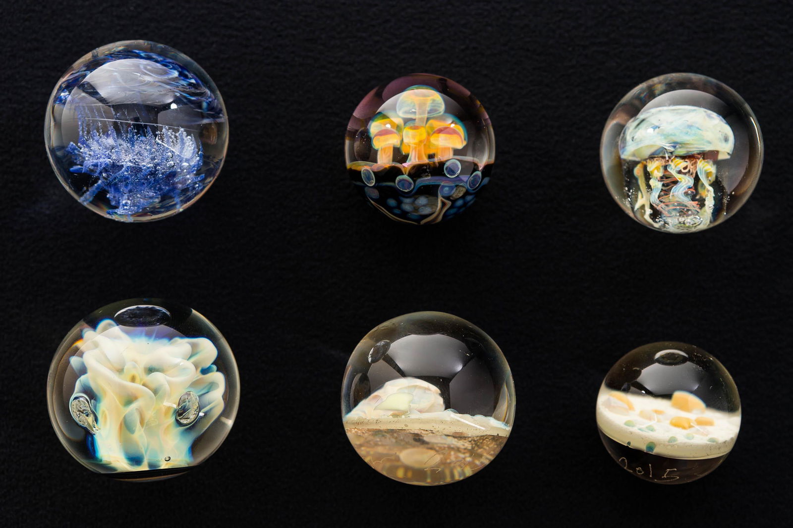 Large Artist Signed Lampwork Glass Marbles: There is a signed "Crisanti" Joseph Crisanti marble with jellyfish interior measuring approx. 34mm diameter; a signed Zariel Shore pink and yellow mushroom interior with starfish on back marble; a mar