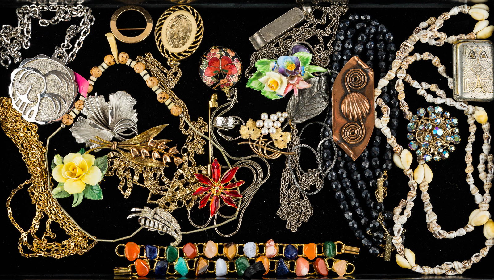 Mixed Costume Jewelry: This collection includes a large silver tone Trifari pendant on a chain, (2) gold tone polished mineral bracelets, a German match safe, Staffordshire floral pins, and other costume jewelry.