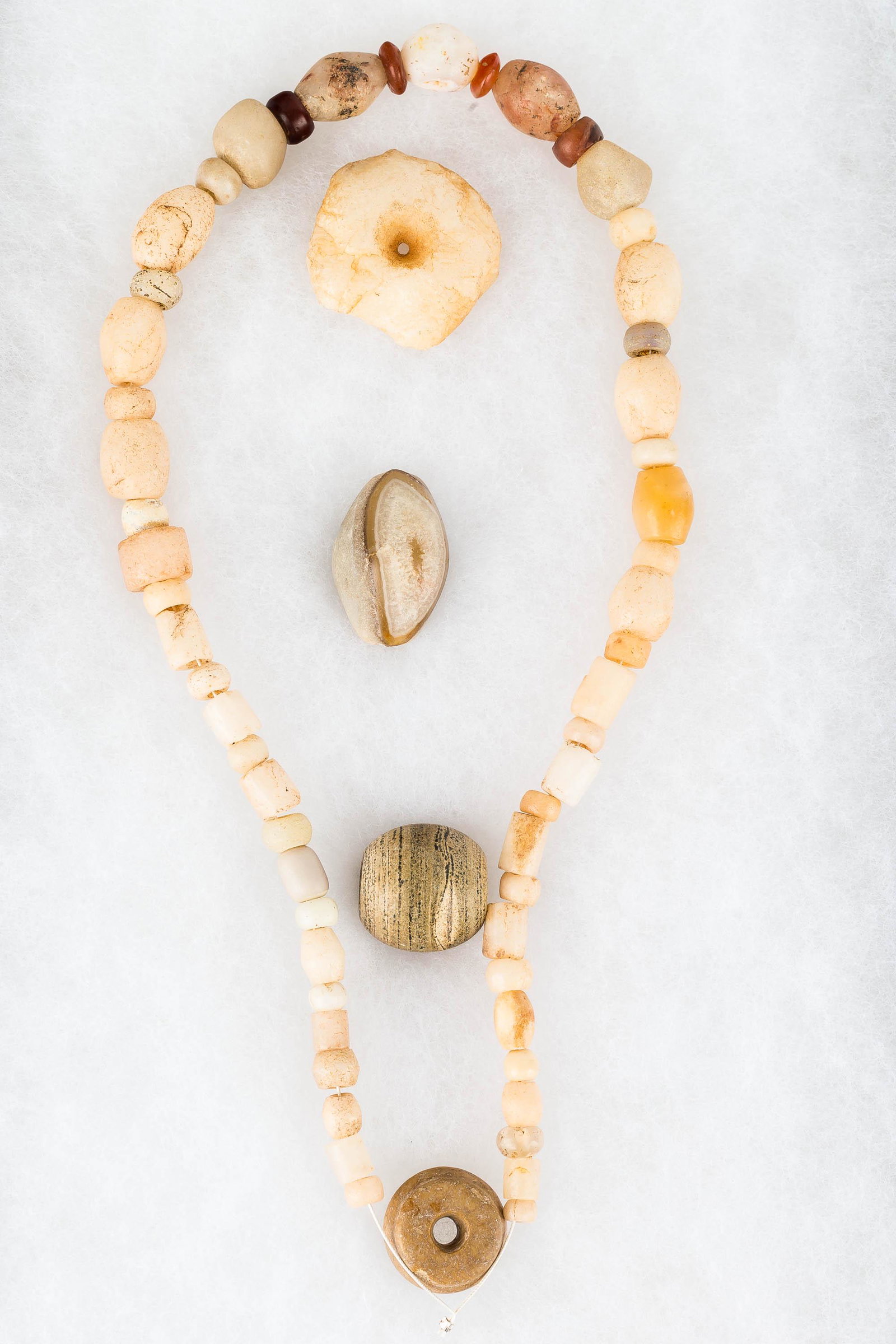 Neolithic Saharan Carved Stone Beads: Beads include quartz, carnelian, and agate; they are biconically hand drilled. One grouping has been made into a necklace, and the largest bead measures approx. 1.5" in diameter.