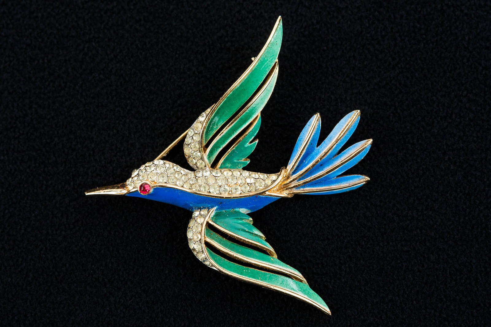 Trifari Enameled Bird Pin: This blue and green enameled pin has clear rhinestones and a red rhinestone eye. It is marked "Trifari" and measures approx. 2"L x 2"H.