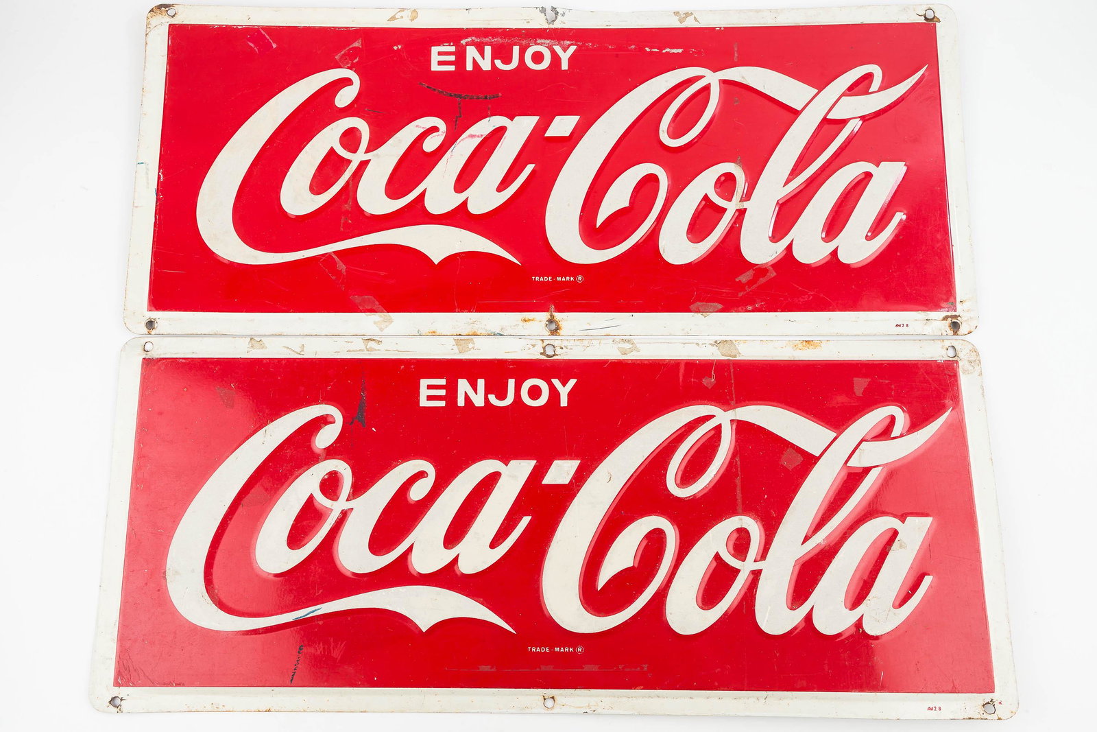 Vintage Pressed Tin Coca-Cola Signs (Pair): There is a pair of heavy pressed tin Coca-Cola signs. They are galvanized metal with raised graphics. They show common wear and each measures approx. 10"H x 24"W.