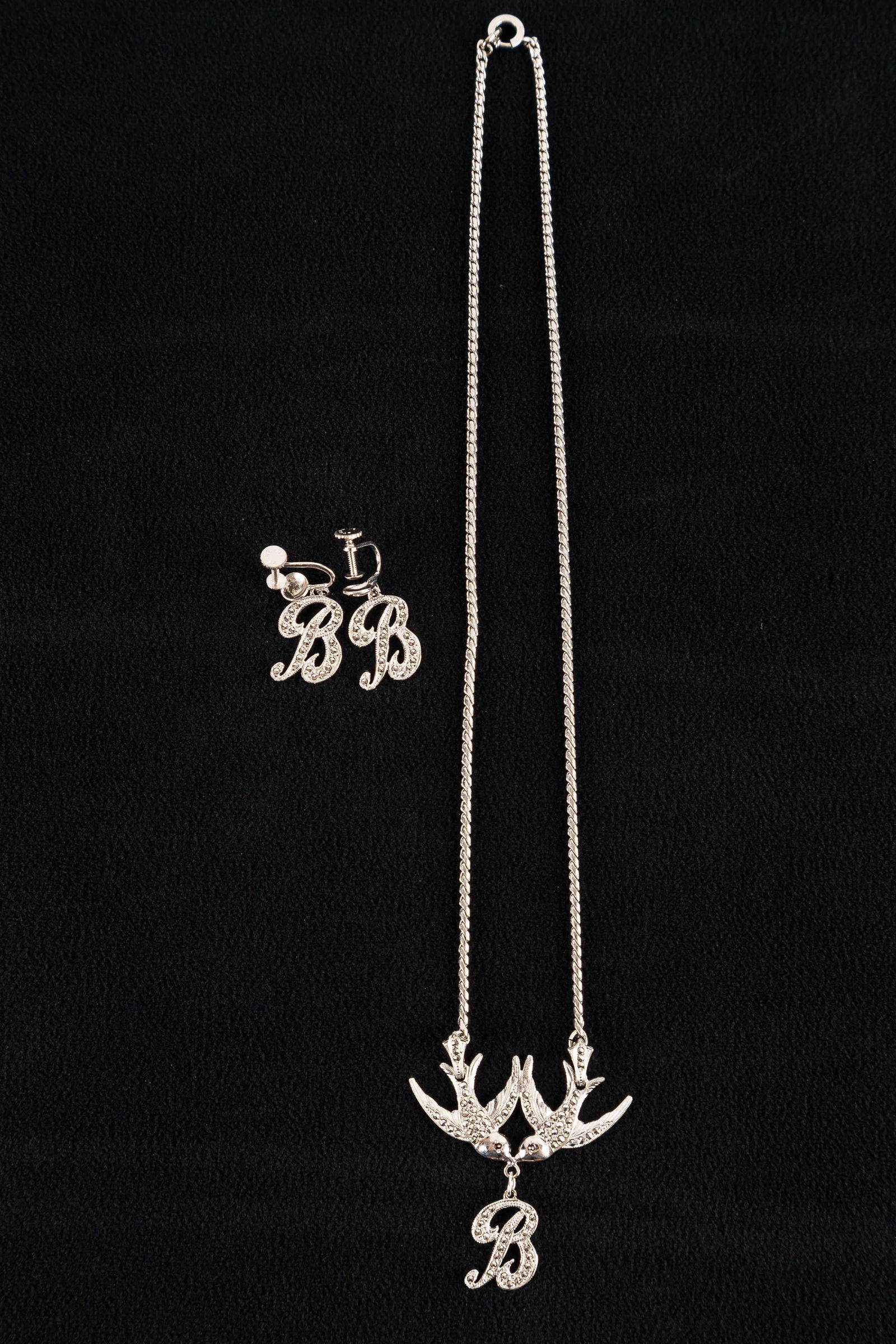 Vintage Sterling Marcasite Jewelry: Circa 1940s sterling silver marcasite necklace with two sparrows holding a letter "B" and matching screwback earrings. Marked Sterling.
