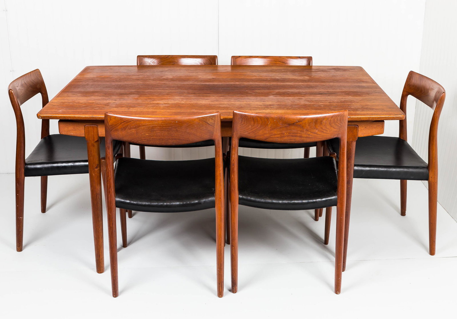 Mid C. Modern Dining Table and Chair Set: This teak Mid Century Modern Danish table and chair set has what appears to be leather or vinyl seats and is Marked by Danish Control, Made in Denmark. Table measures approx 29"H x 58"W x 31"D. It has