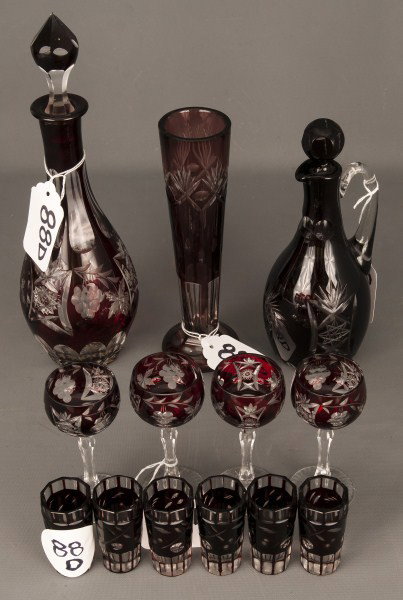 Glass Decanters: Two red cut to clear glass decanters, one with 5 shot glasses, one with four stem glasses and a matching vase