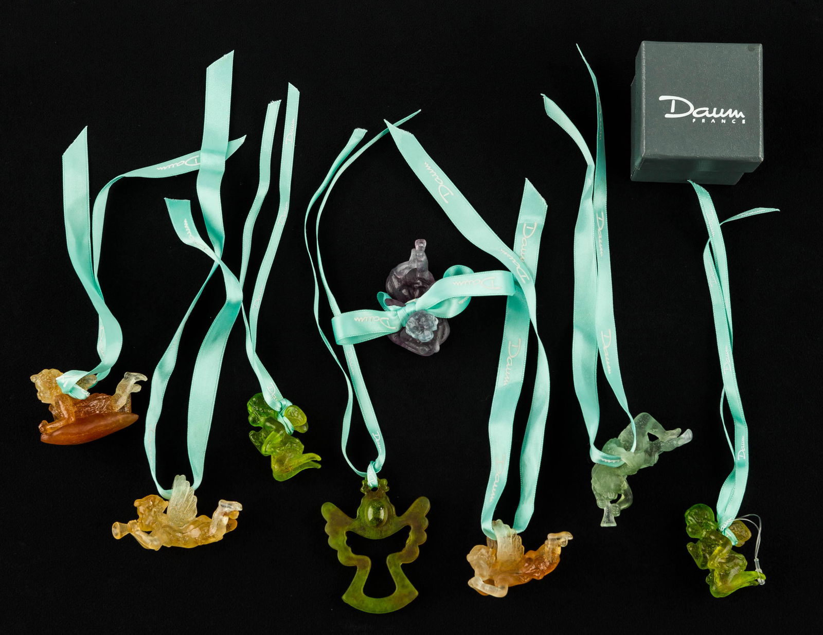 Daum France Pate De Verre Angel Ornaments: 8 Daum France angel ornaments in amber, greens, and purple. 2 angels on cloud in purple and amber with Daum France etched on bottom, 3 trumpeting angels in sea green and amber with wing loops etched D