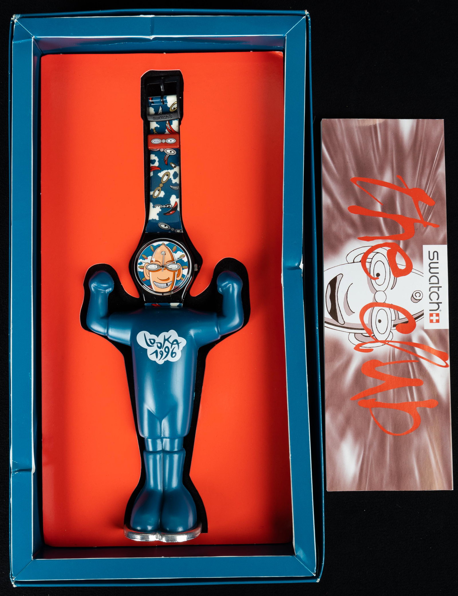Swatch 'The Club' Looka Face Watch: This Swatch Looka faced watch with holder features an face changing Looka wrist watch with original box and instructions. Face on watch changes expressions as time goes on. Untested.