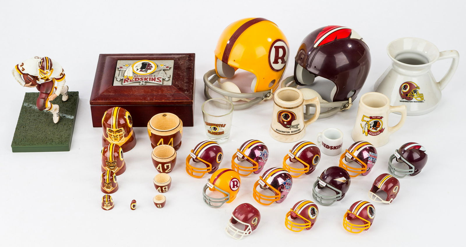 Washington Redskins Souvenirs: 14 mini helmets in various sizes, matryoshka type nesting doll, with Taylor, Riggins, Jurgensen, and Mitchell, various drinking vessels, box, and a Riggins figure.