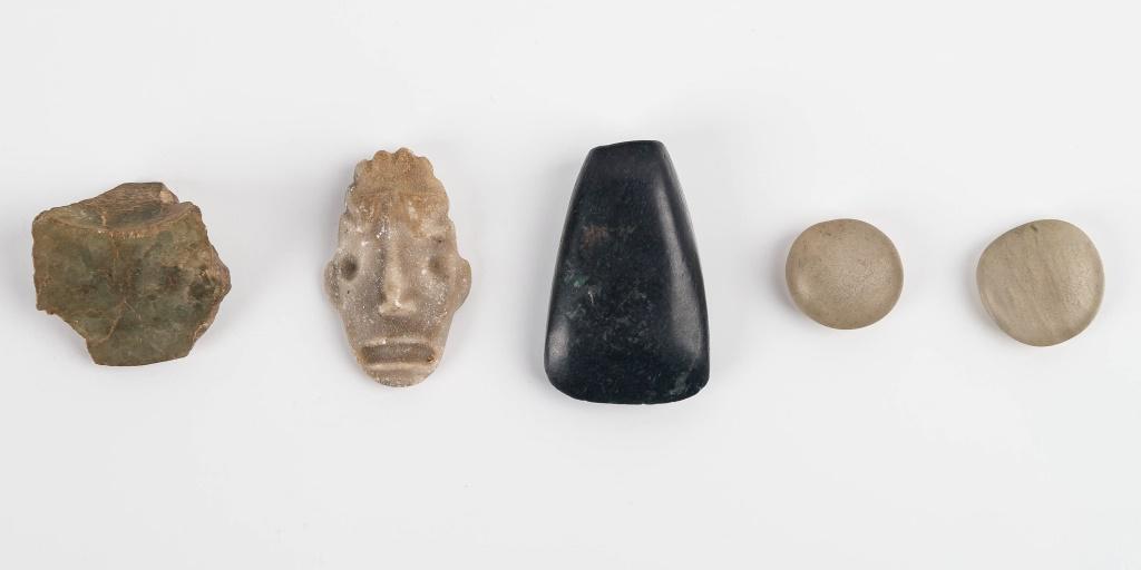 Pre-Columbian Jade and Stone Artifacts: Five items including a dark green jade axe approx 1.75" L, two white jade game pieces, a chunk of jade possibly from a mask. The stone masquette is sandstone and the age is not sure because of the sha