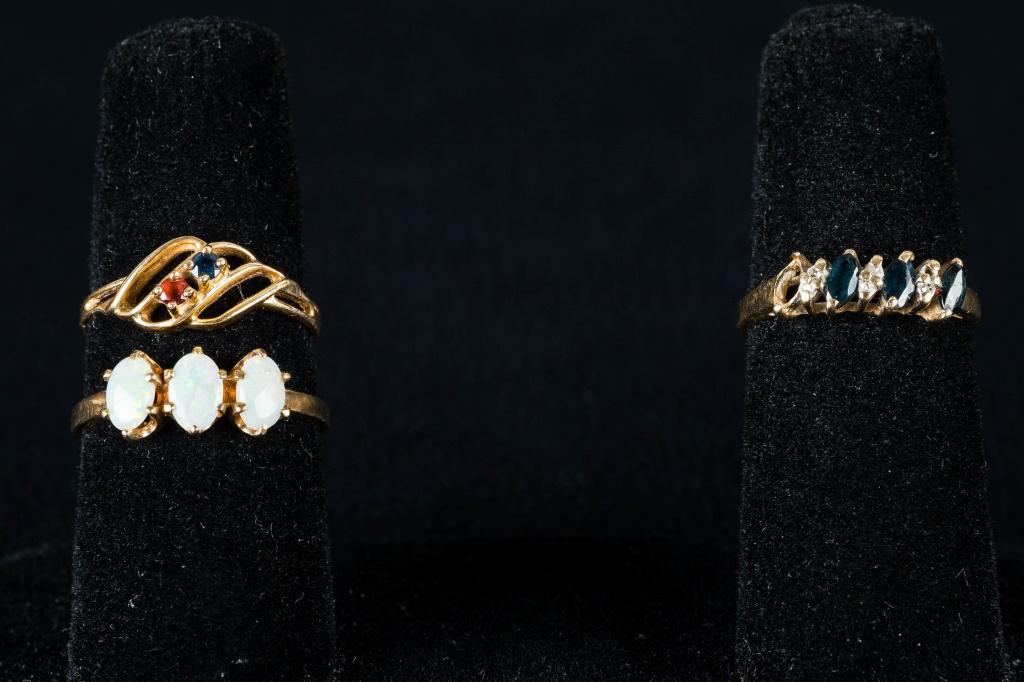 10K Gold Rings with Stones: Ring marked 14K FLN has diamond and topaz stones, missing one topaz, size approx 7; an opal ring is marked 10k is approx 8; and a topaz and tanzanite 10k ring is approx size 7. Total weight approx 3.9