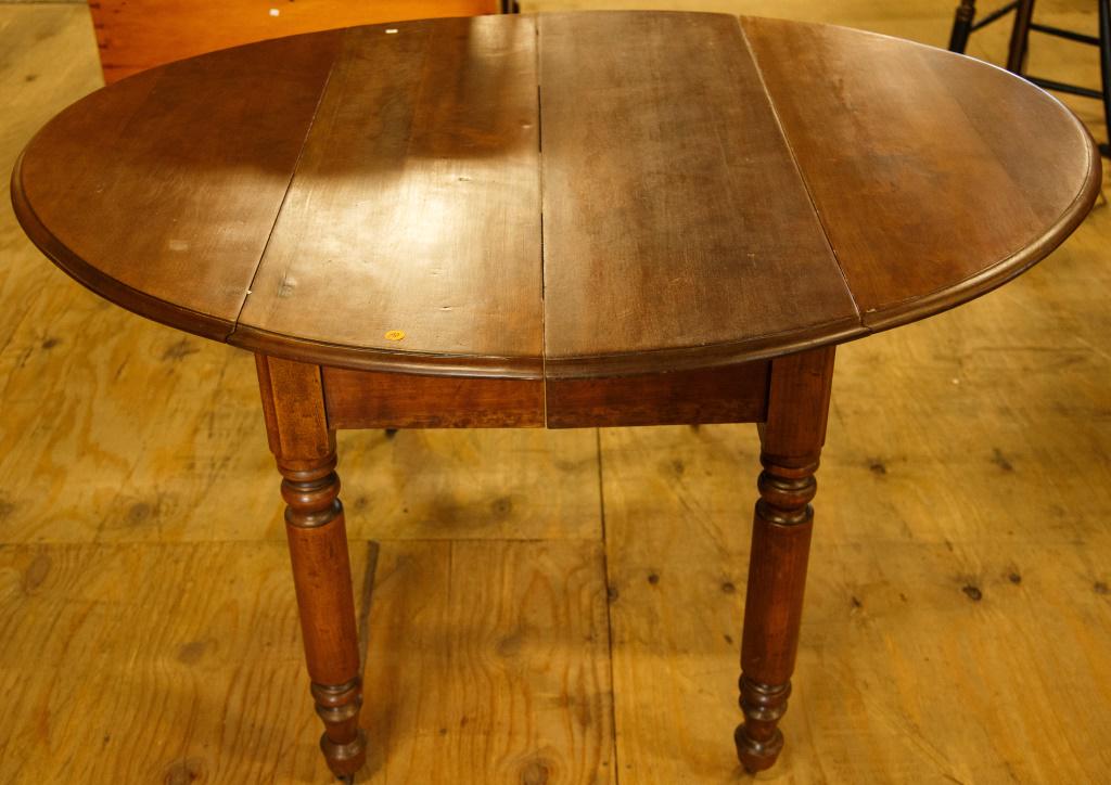 Round Walnut Drop Leaf Table: Turned legs, casters, measures 29" high x 53" wide (open) x 44" deep.